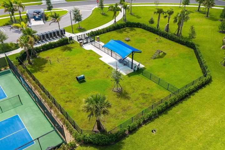 Fenced green space with a shaded structure, paved pathways, and recreational equipment