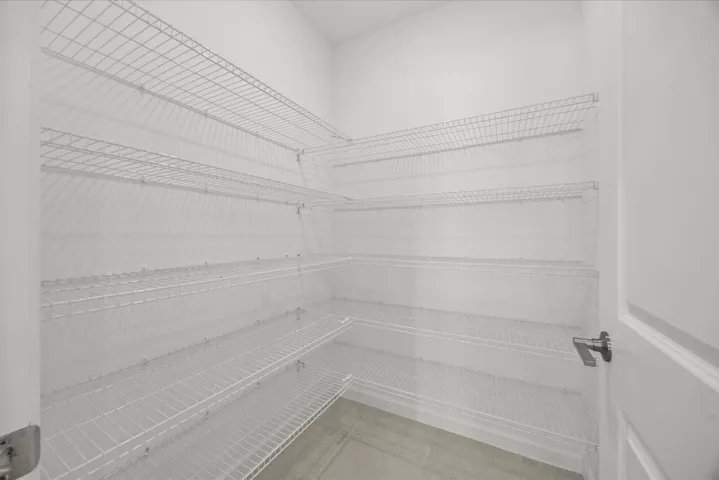 Walk-in pantry featuring multiple levels of wire shelving and a finished floor