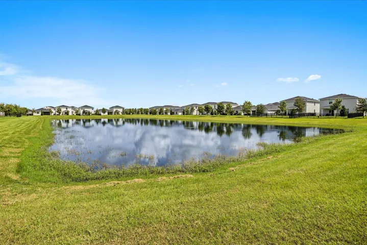 Expansive green space featuring a natural pond and surrounding residential structures