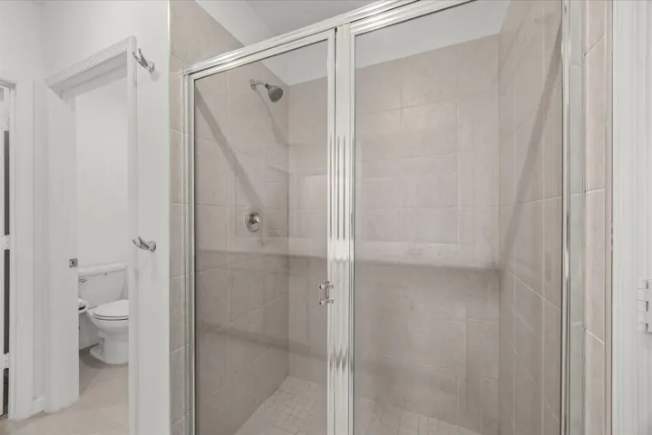Glass-enclosed shower with tile surround and integrated shower head