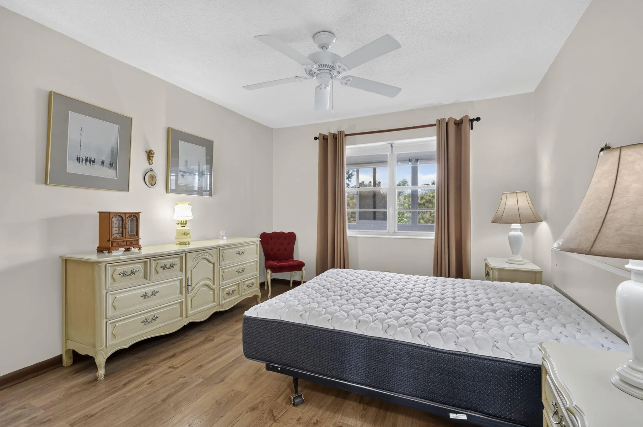 Neutral wall color, wood-finish flooring, white ceiling fan with integrated lighting, and a multi-pane window