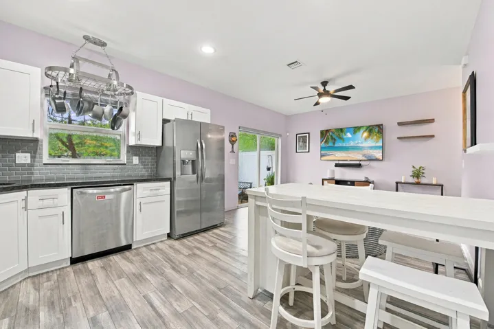 Kitchen featuring stainless steel appliances, white cabinetry, dark countertops, and a gray subway tile backsplash