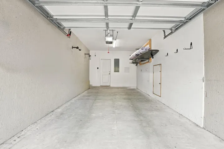 Spacious garage with concrete flooring, overhead lighting, and an interior access door