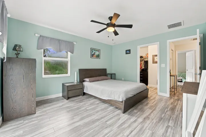 Room featuring wood-finish flooring, a ceiling fan with integrated lighting, and a single window