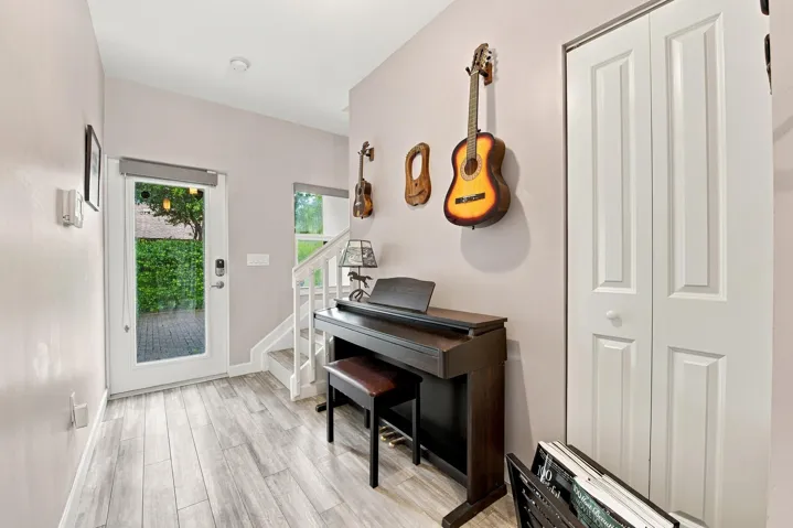 Wood-finish flooring, white paneled bifold closet doors, and a full-light entry door with integrated blinds