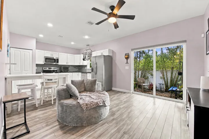 Open-concept kitchen and living area with wood-finish flooring, recessed lighting, and a ceiling fan