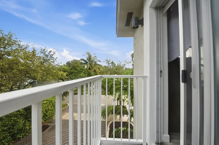 Balcony featuring a white metal railing, exterior wall sconce, and sliding glass door