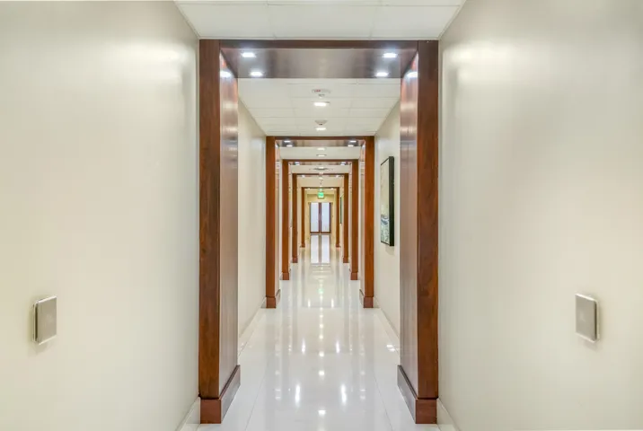 Long hallway featuring wood-finish door frames, recessed ceiling lighting, and polished flooring