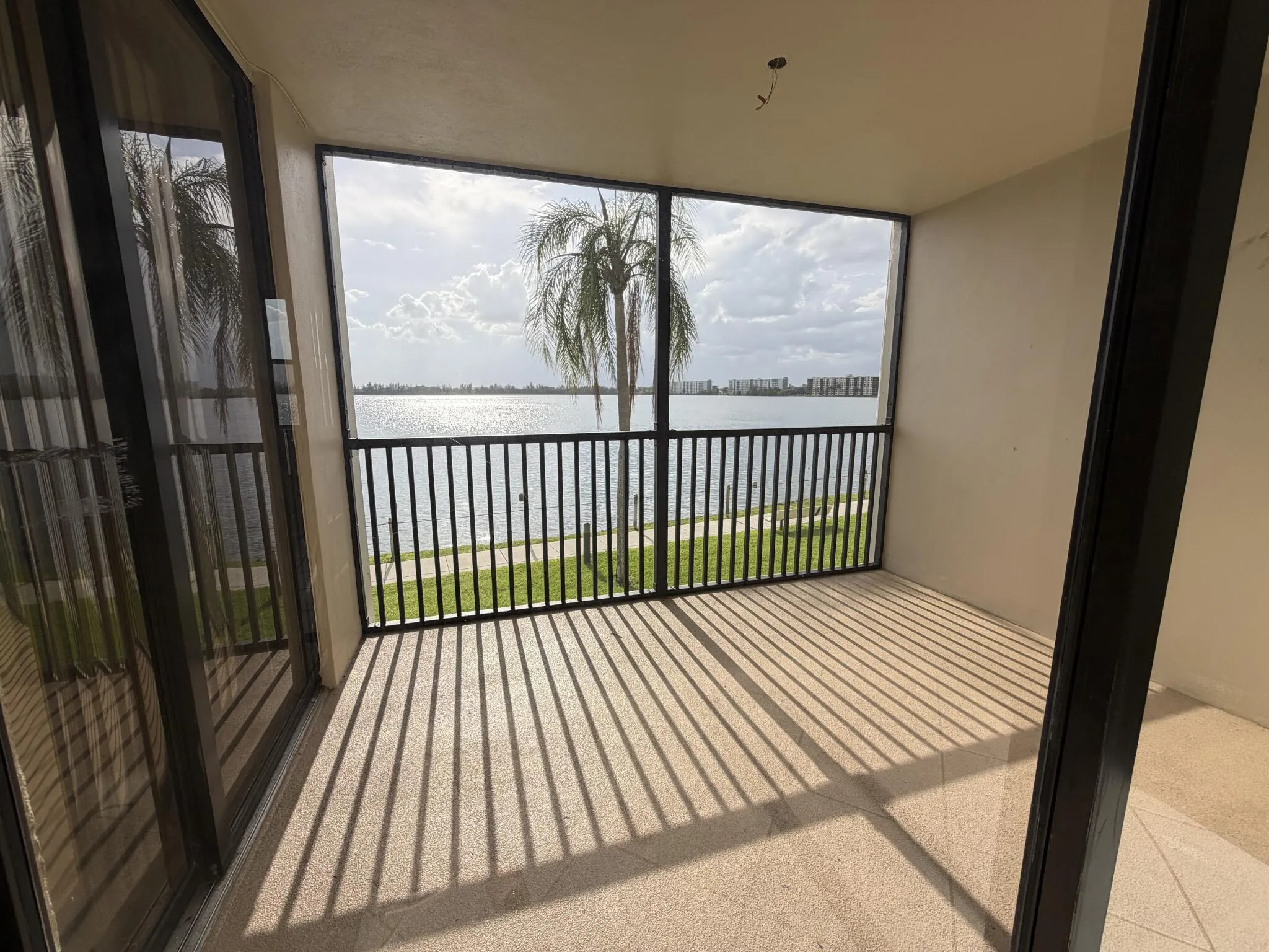 Screened balcony featuring tiled flooring, black metal railing, and expansive water frontage