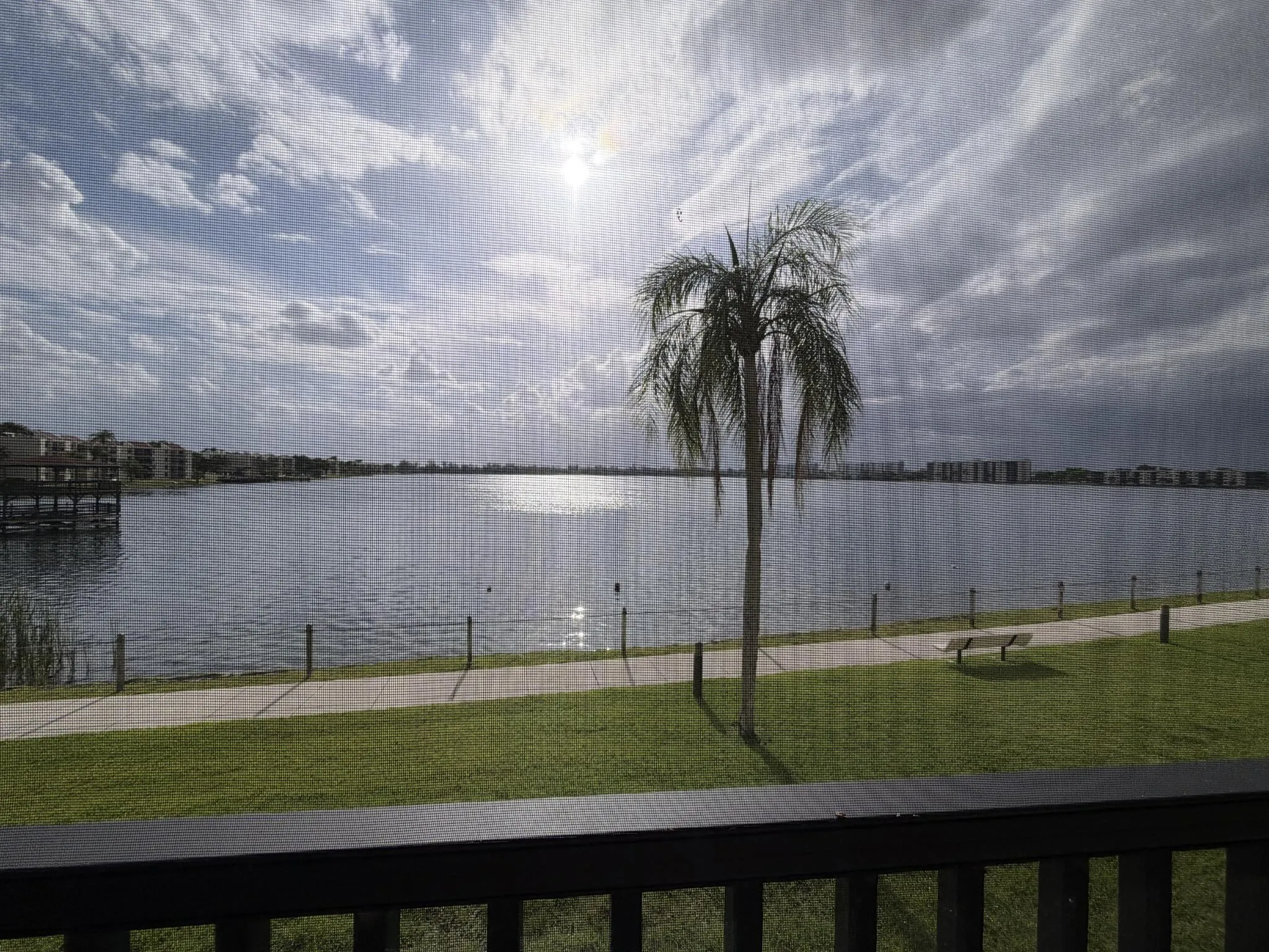Expansive water feature with a paved walkway and green space