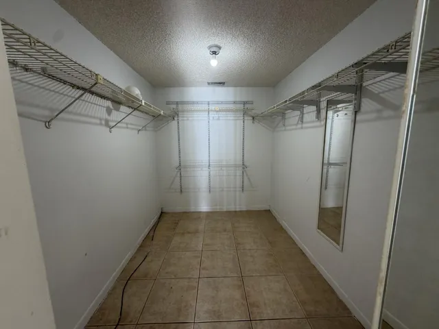 Spacious walk-in closet featuring tiled flooring, wire shelving, and a full-length wall-mounted mirror
