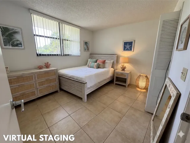 Tile flooring in a neutral tone, featuring a window with vertical blinds, and a built-in louvered closet door