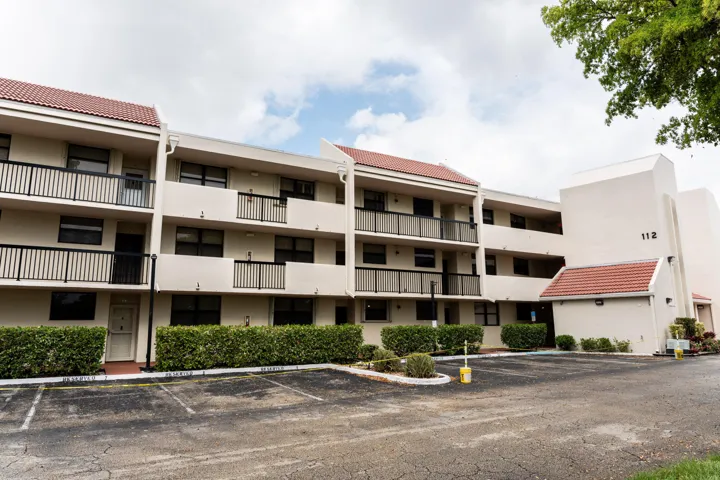 Multi-story building featuring tile roofing, multiple balconies with black railings, and a stucco exterior finish