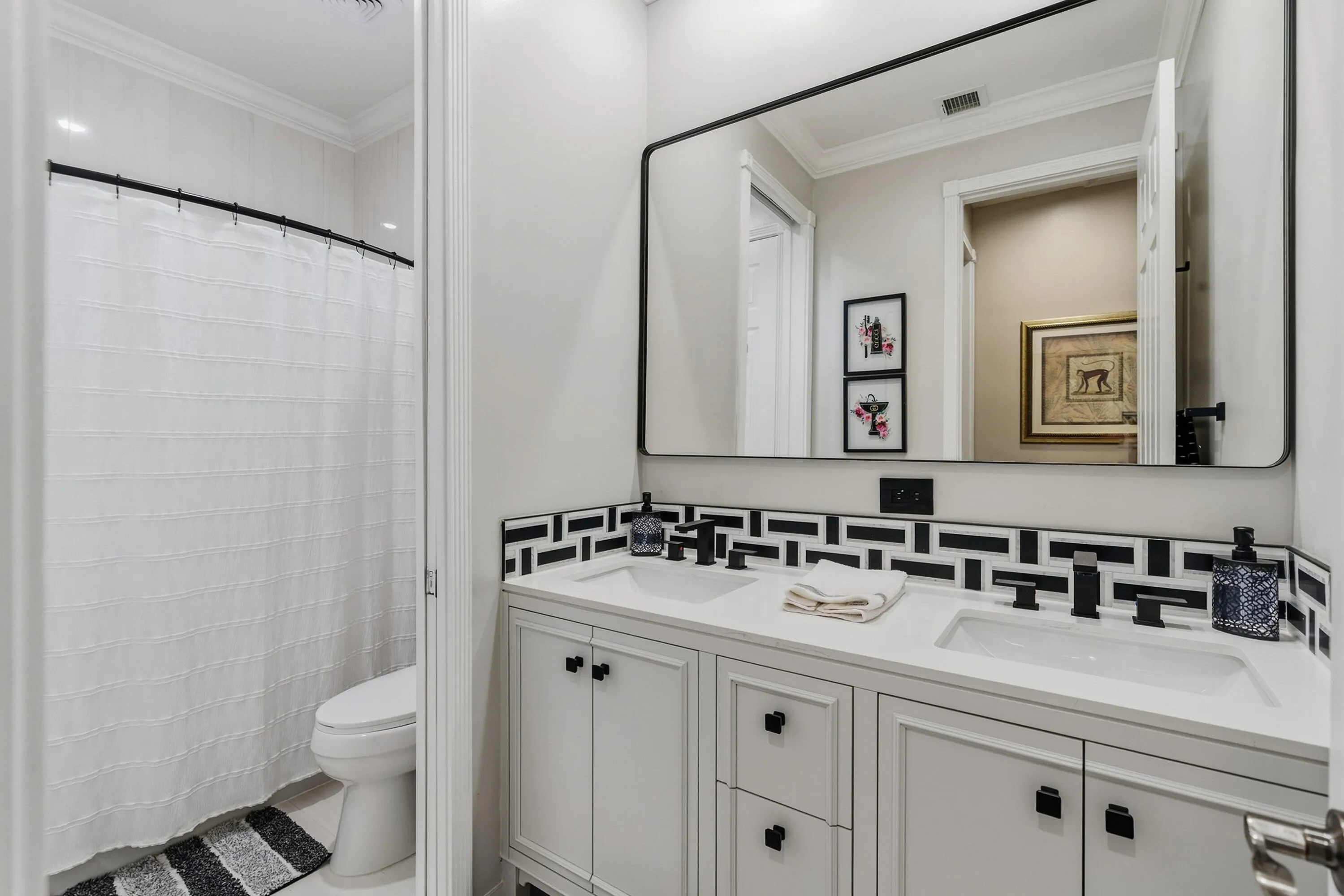 Newly renovated upstairs bathroom features a dual-sink vanity, modern black fixtures and contemporary finishes.