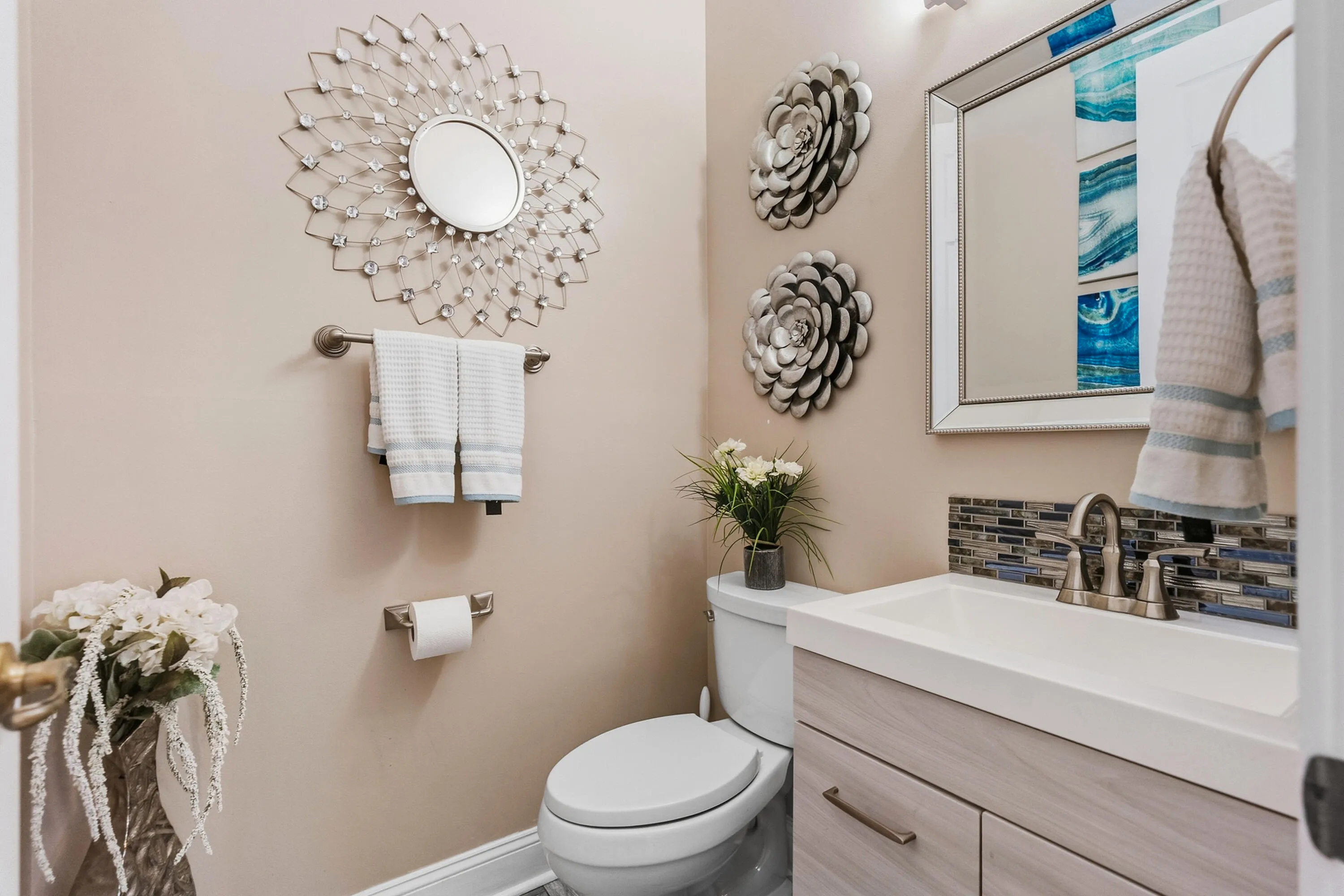 Stylish half bathroom features an updated vanity, decorative tile backsplash and contemporary finishes.