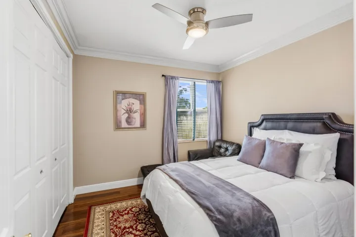 Comfortable upstairs bedroom with wood flooring, crown molding, closet space and room for a queen-size bed.