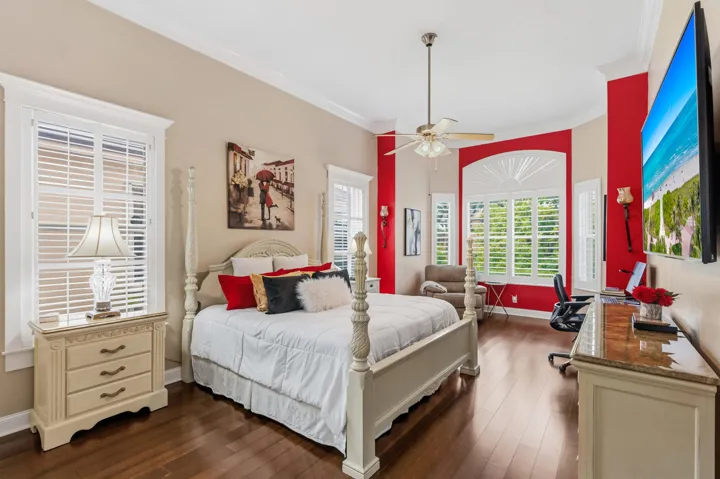 Spacious downstairs primary bedroom with high ceilings, with crown molding, engineered hardwood flooring, and plantation shutters for adjustable natural light and privacy.