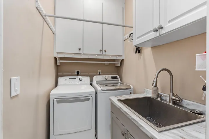 Well-equipped laundry room with updated washer and dryer, utility sink and abundant built-in cabinetry for added storage.