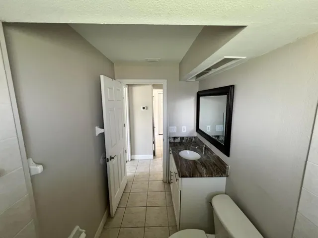 Bathroom featuring a vanity with a dark stone countertop, white oval undermount sink, and a framed mirror