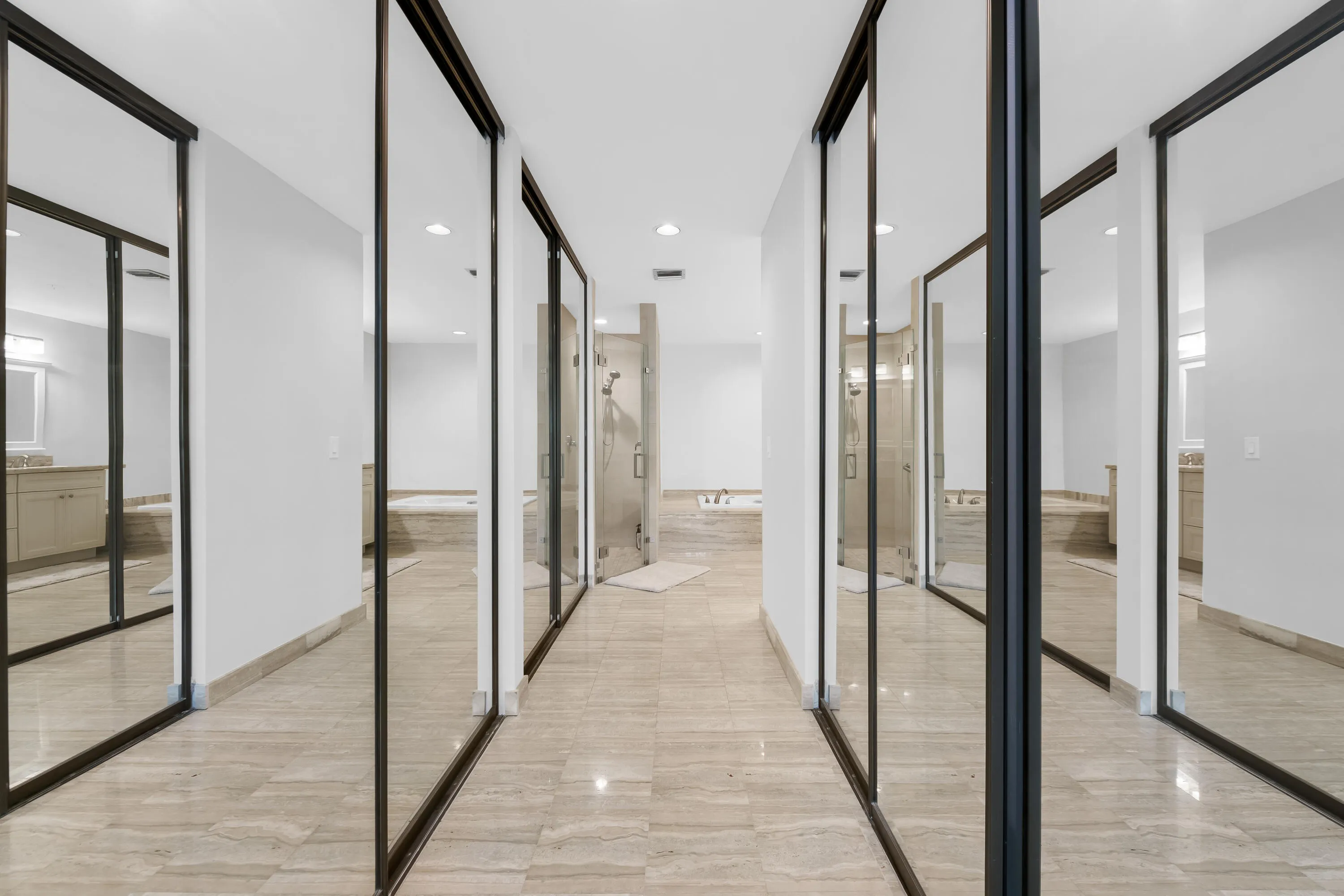 Hallway with mirrored closet doors, tiled flooring, recessed lighting, and a partial bathroom featuring a built-in tub