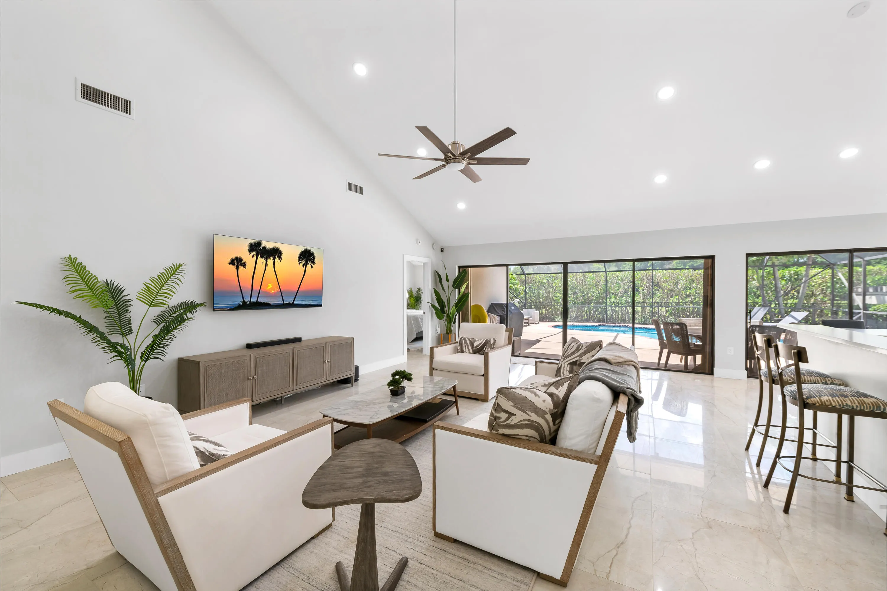 Vaulted ceilings with recessed lighting, ceiling fan, large format tile flooring, and expansive sliding glass doors opening to outdoor living space