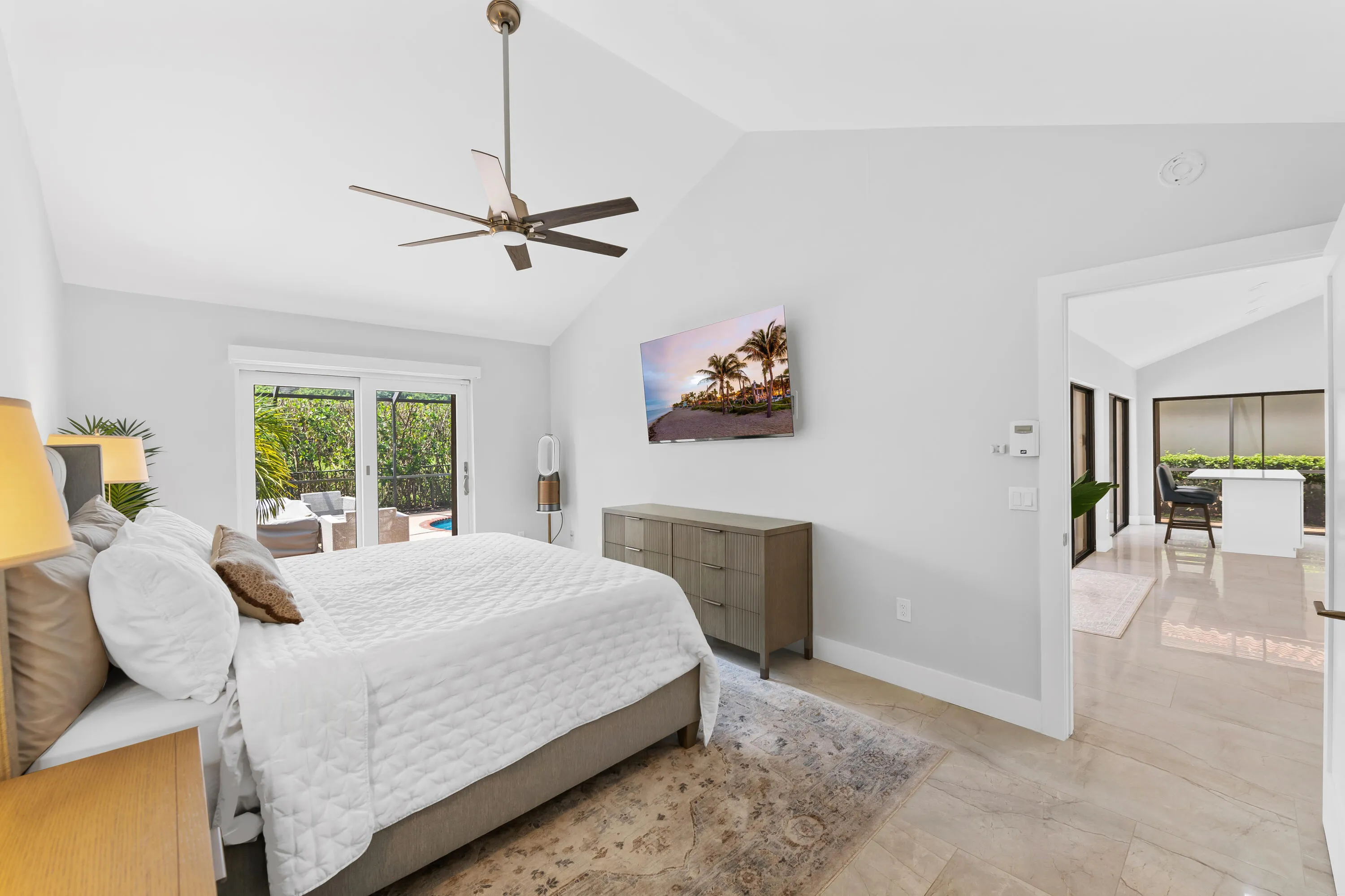 Vaulted ceiling with a ceiling fan, sliding glass doors to outdoor living, light-tone tile flooring, and a doorway to another room