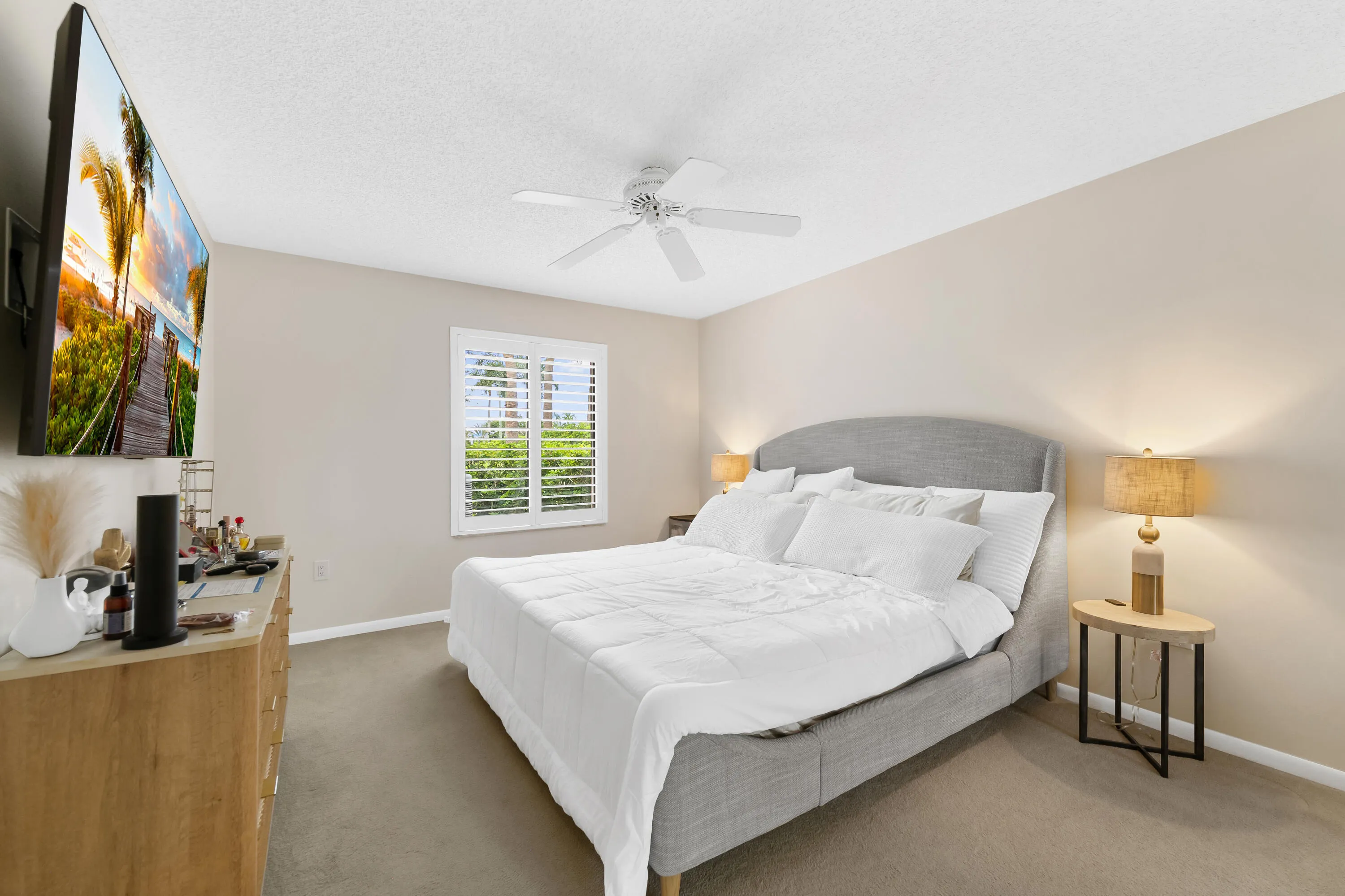 Window with white plantation shutters, neutral tone walls, and ceiling fan
