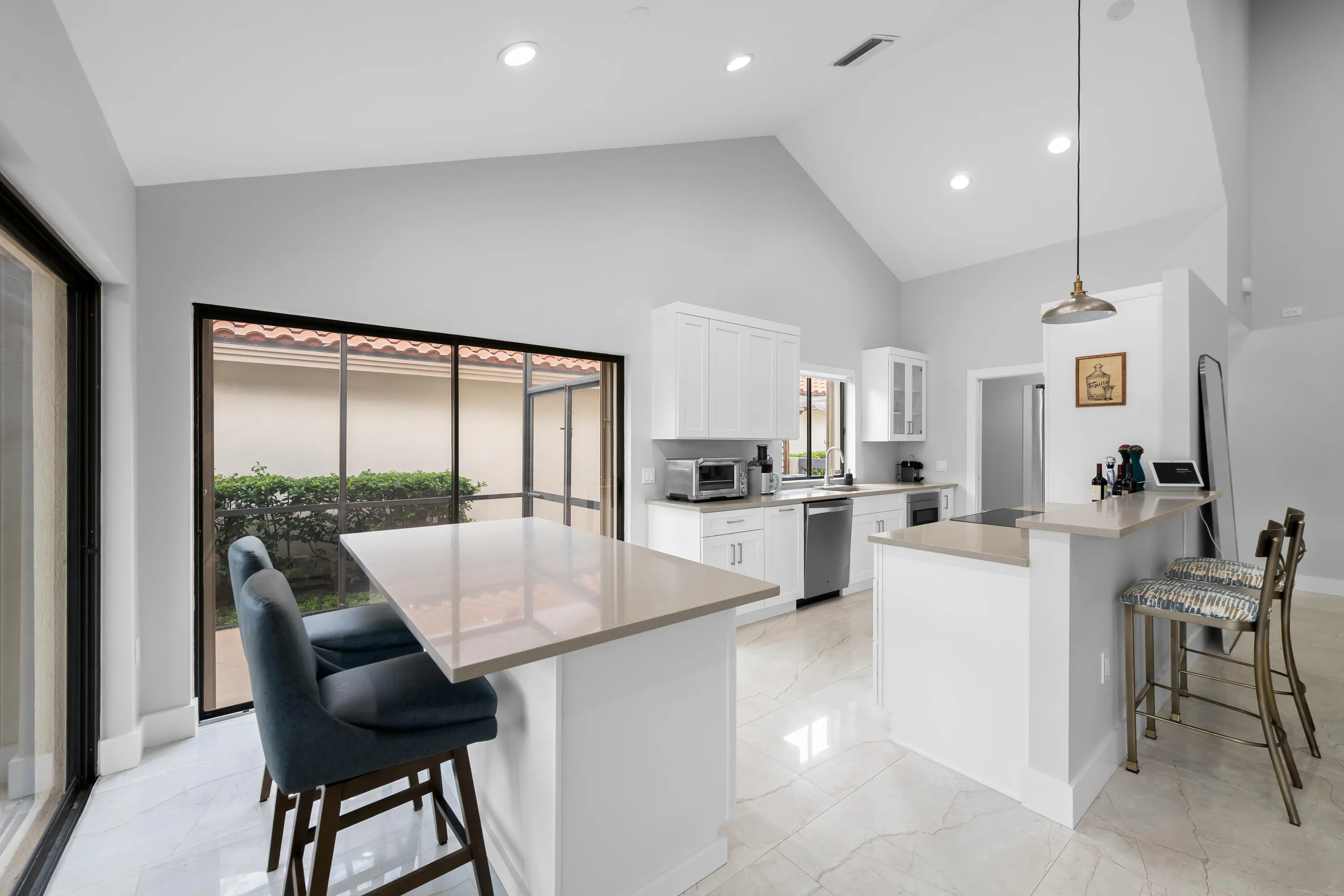 Vaulted ceiling, recessed lighting, white cabinetry, stainless steel appliances, and large format floor tiling
