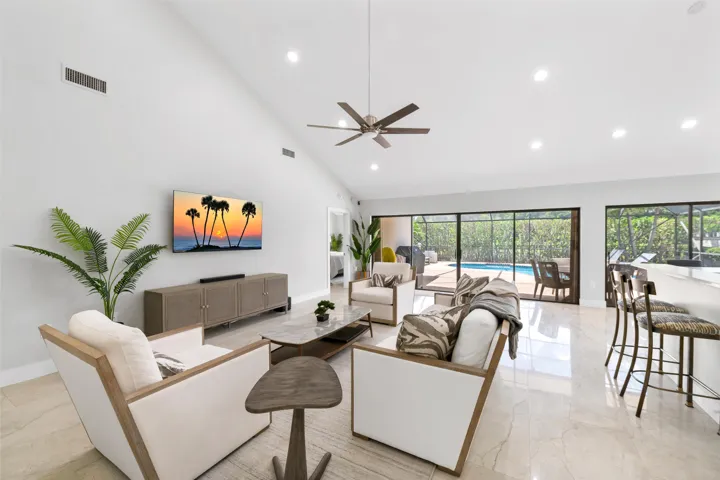 Vaulted ceilings with recessed lighting, ceiling fan, large format tile flooring, and expansive sliding glass doors opening to outdoor living space