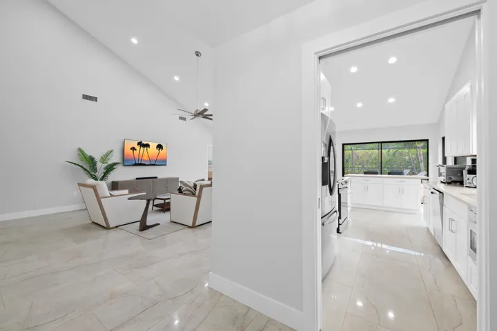 Vaulted ceilings with recessed lighting, large format tile flooring, contemporary ceiling fan, and a kitchen featuring white cabinetry and stainless steel appliances