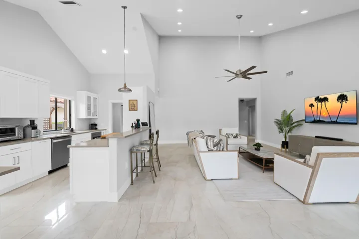 Vaulted ceilings, recessed lighting, and a modern ceiling fan complement the open-concept design