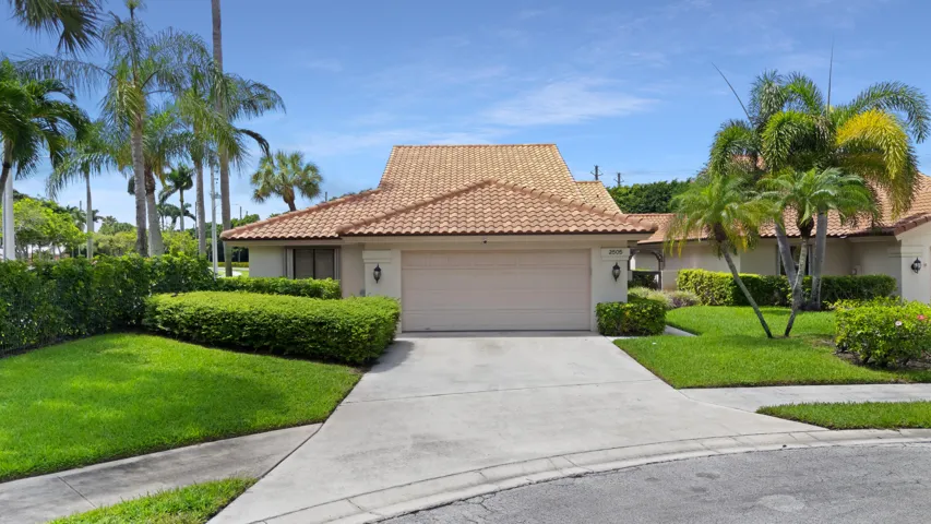 Mediterranean-style residence featuring a terracotta tile roof, attached garage, and a concrete driveway