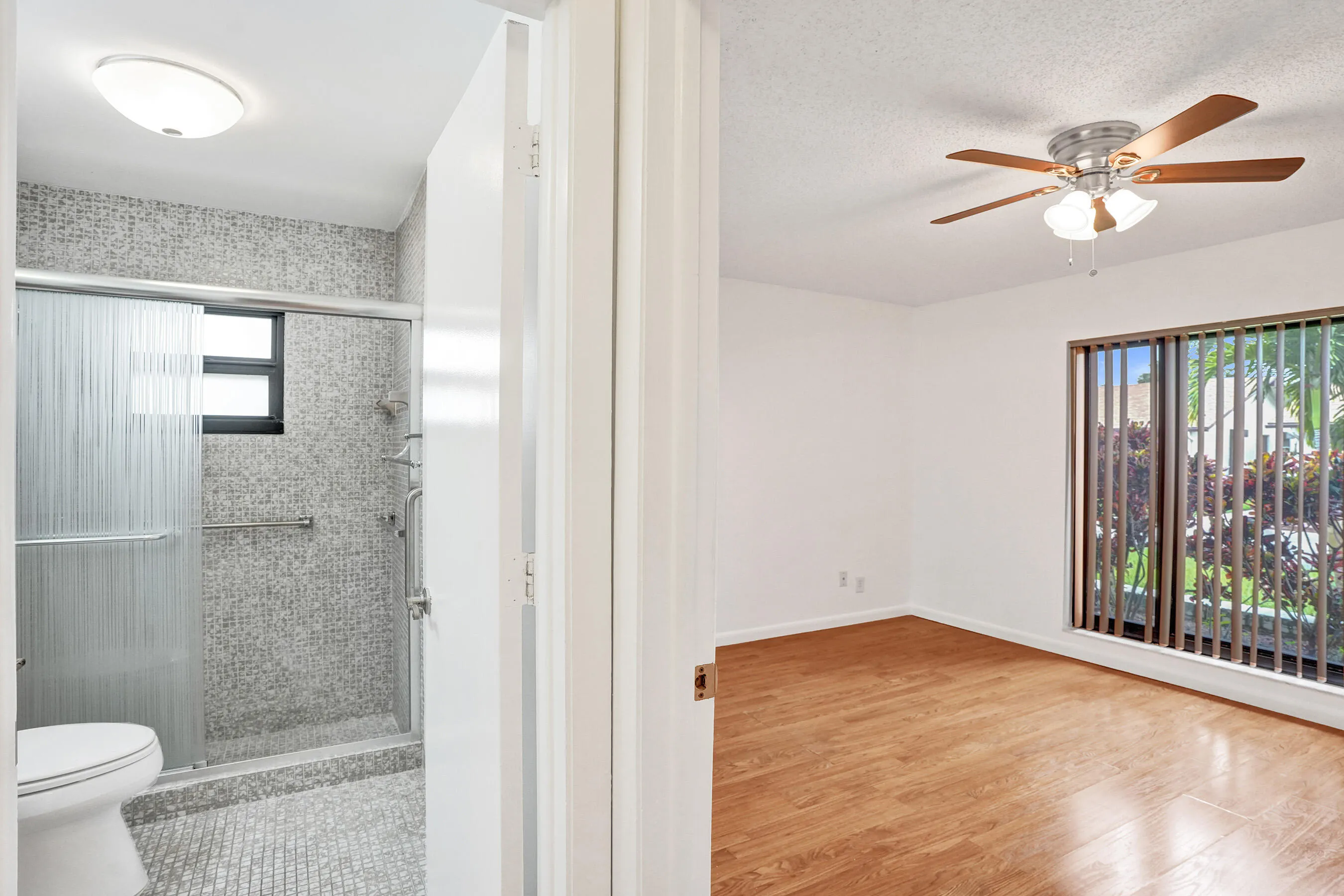 Bathroom featuring a shower with glass sliding doors, mosaic tile surround, and a fixed window