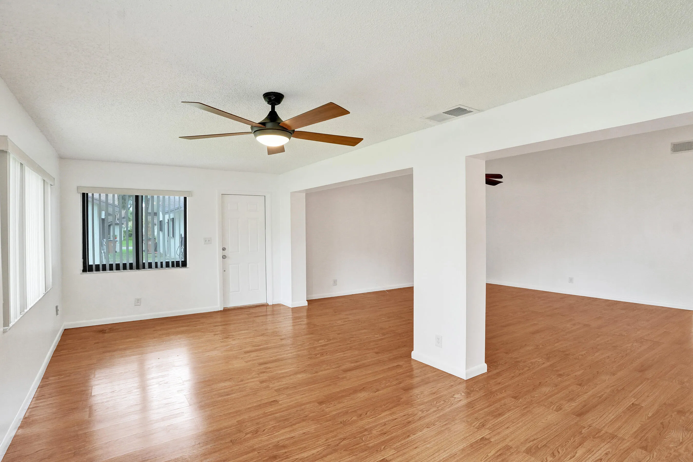 Wood-finish flooring throughout, bright white walls, and a ceiling fan with integrated lighting