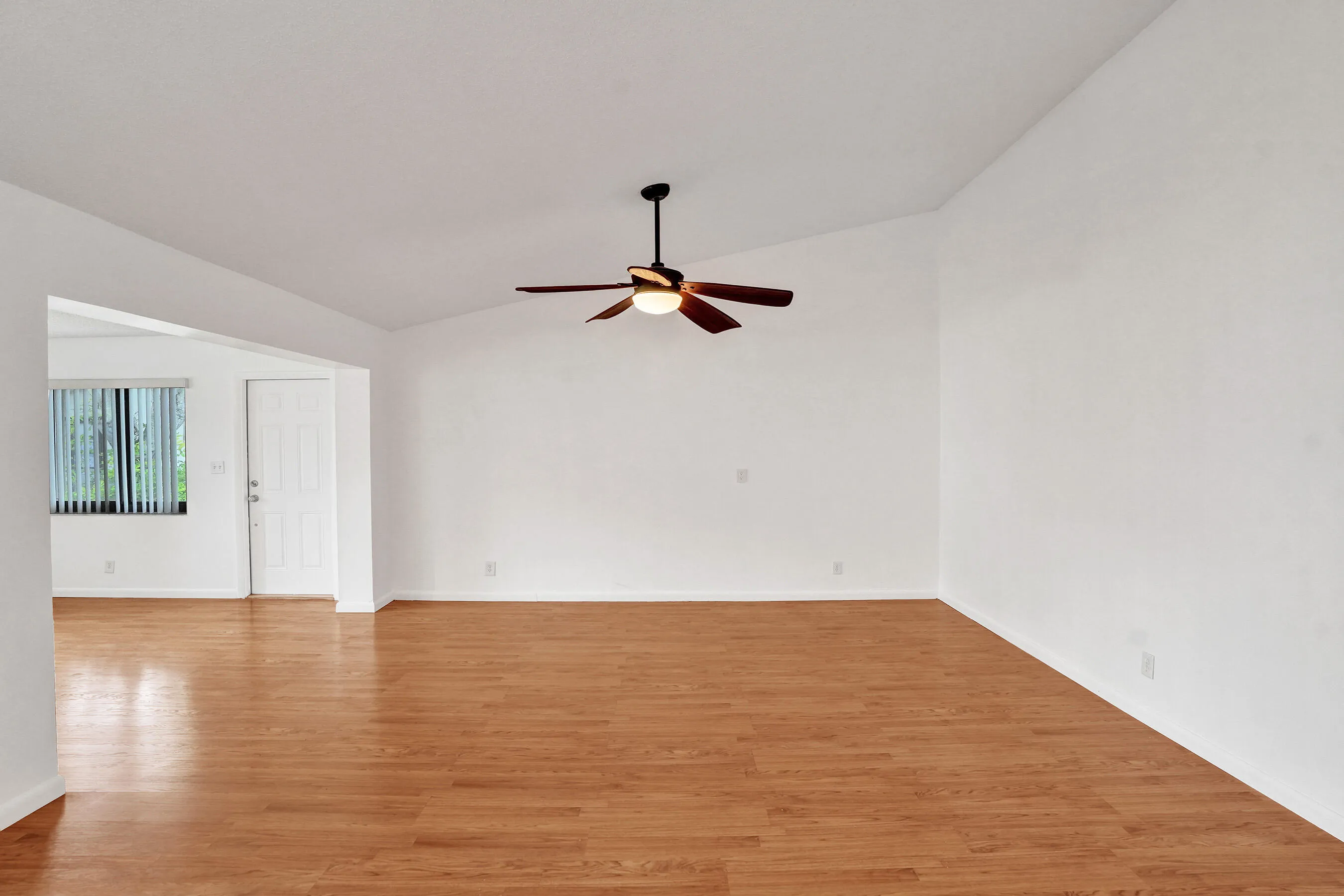 Wood-finish flooring, vaulted ceilings, and a ceiling fan with integrated lighting