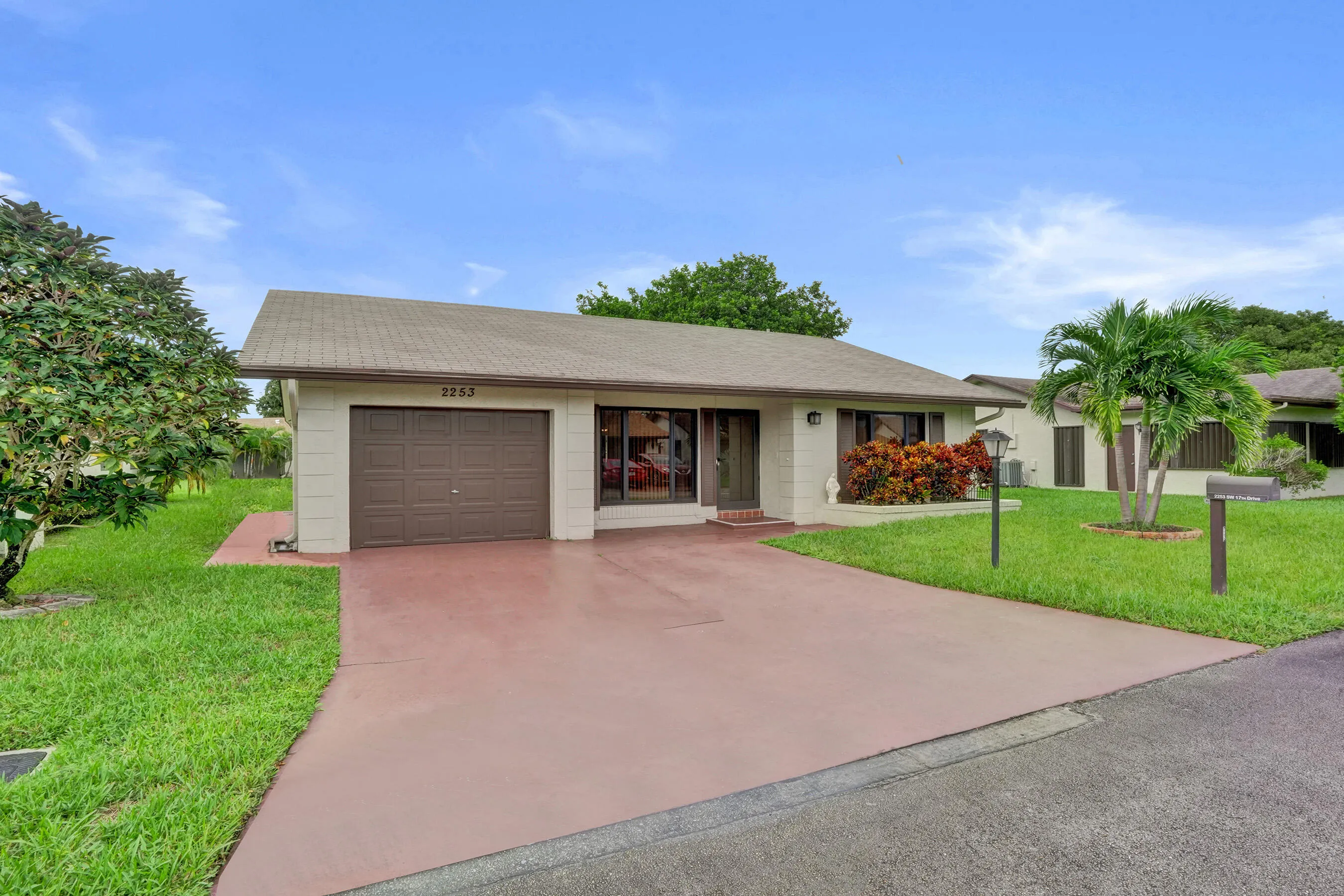 Single-story residence featuring a two-car garage, a concrete driveway, and mature landscaping