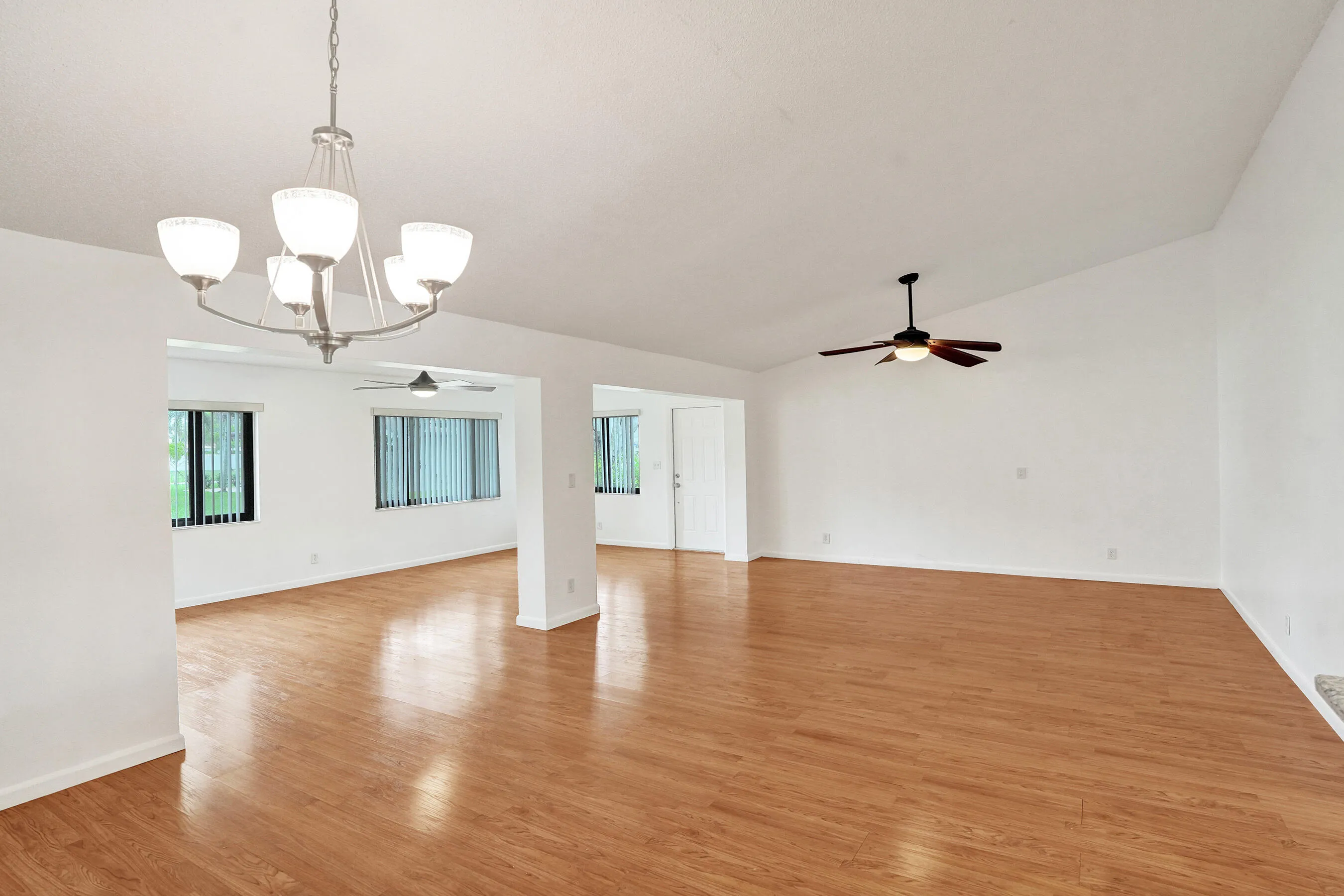 Vaulted ceiling with a ceiling fan, wood-finish flooring, recessed lighting, and multiple windows with vertical blinds