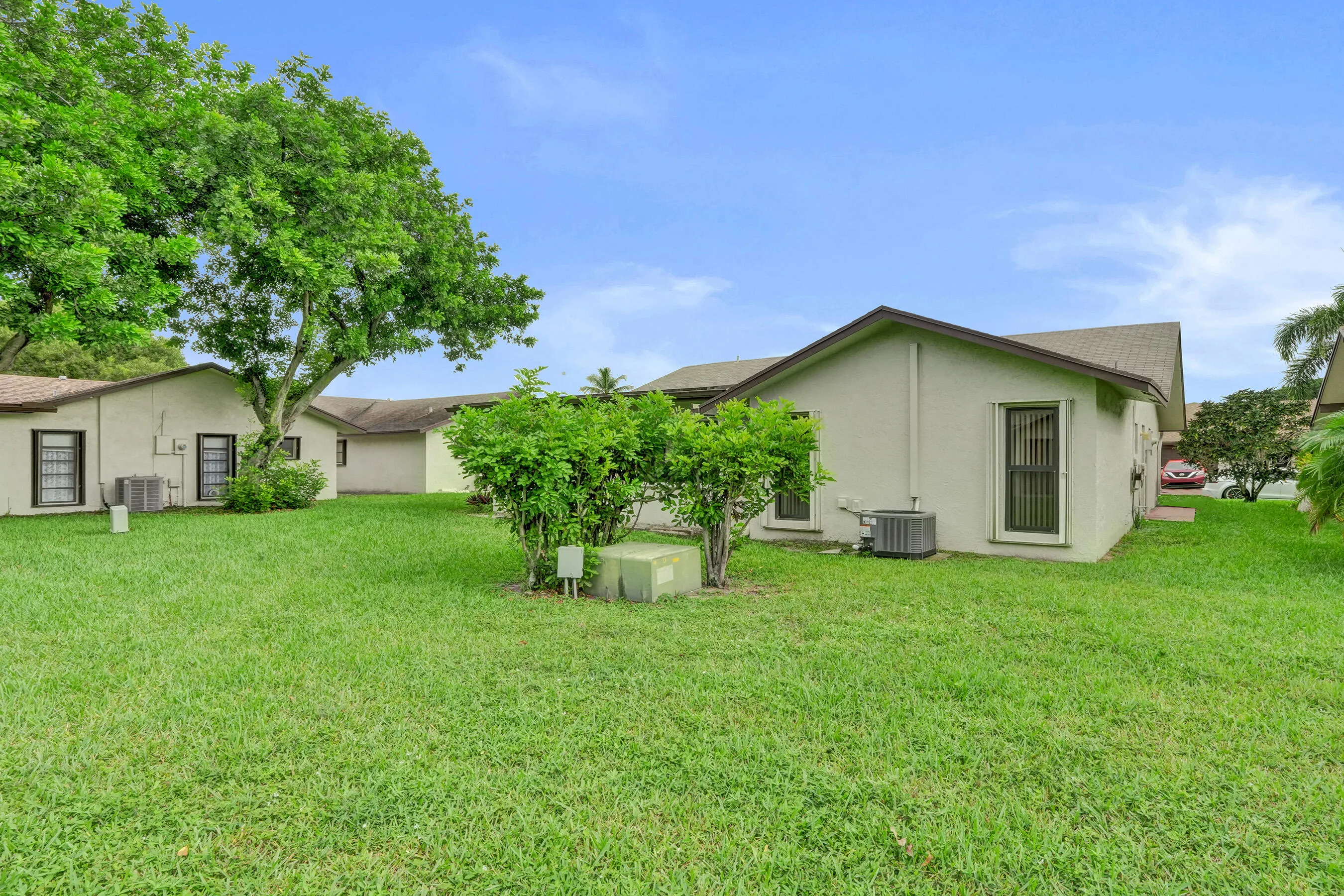 Expansive green lawn with mature trees and established perimeter shrubbery
