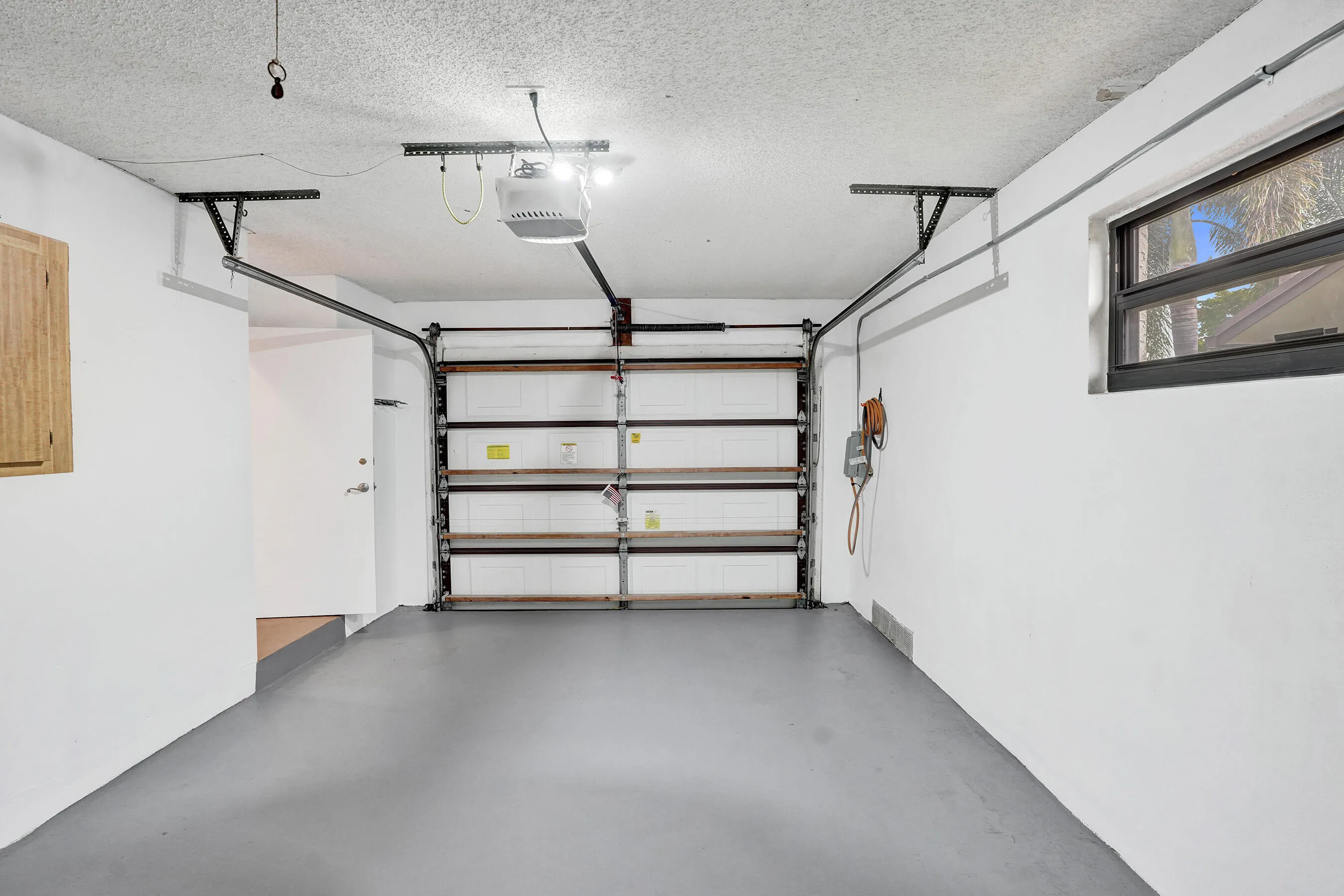 Attached garage with light gray flooring and a window