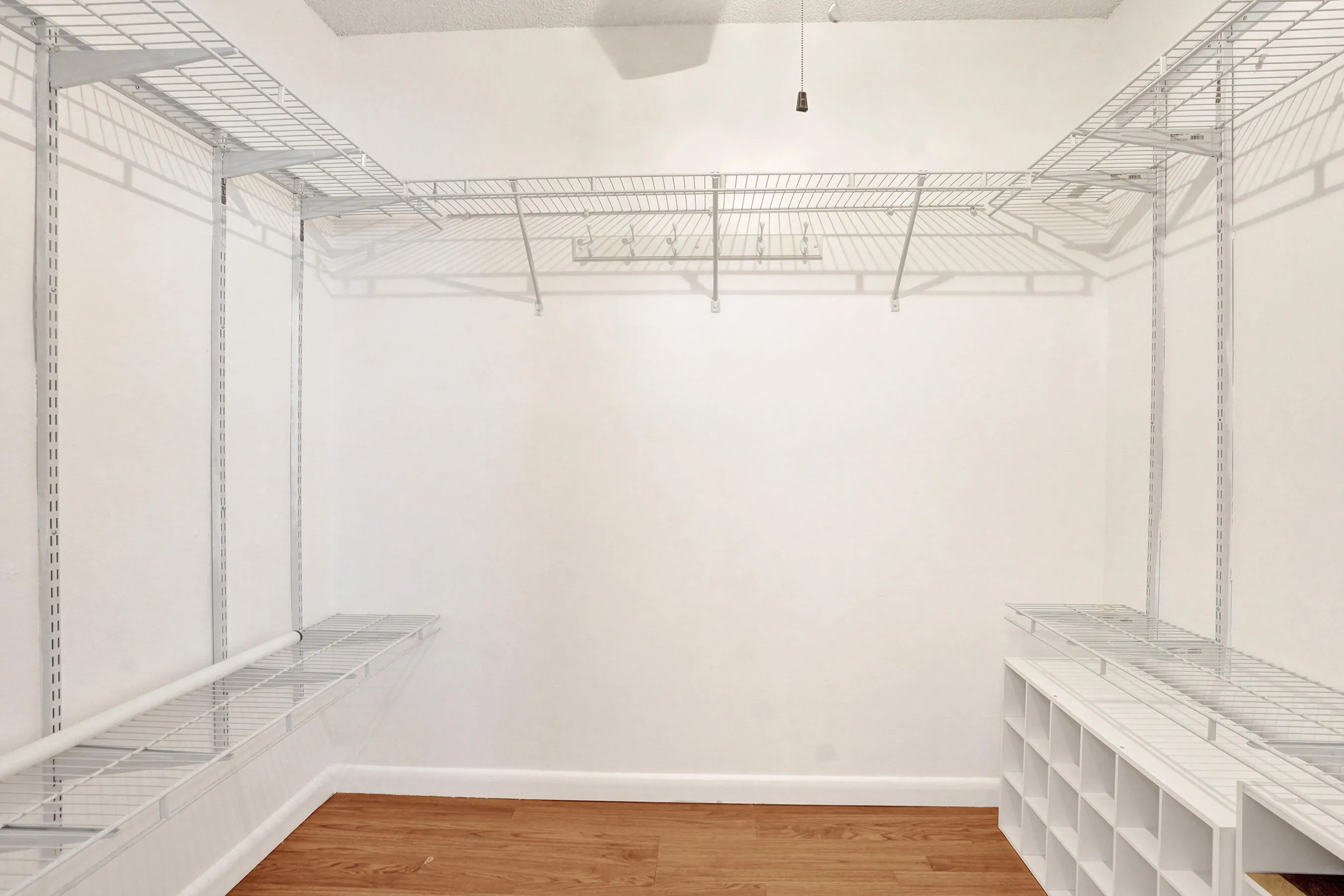 Integrated wire shelving system, built-in shoe cubbies, wood-finish flooring, and white baseboards