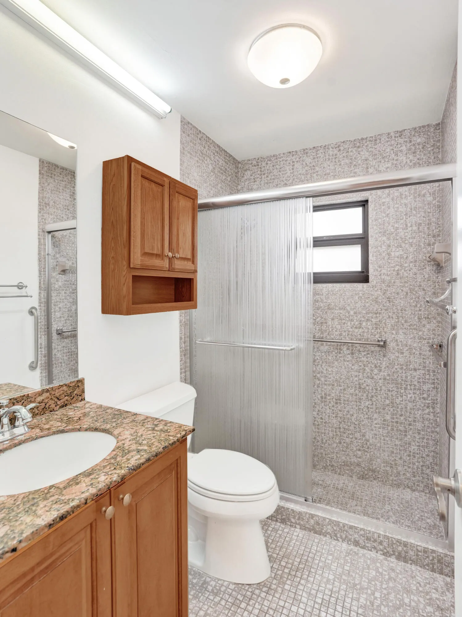 Full bathroom featuring a walk-in shower with sliding glass doors, mosaic tile walls, and a window for natural light