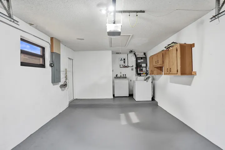 Utility area with painted concrete flooring, wall-mounted cabinetry, and a window for natural light