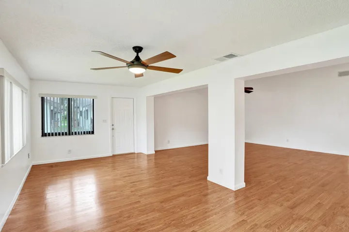 Wood-finish flooring throughout, bright white walls, and a ceiling fan with integrated lighting