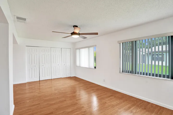 Wood-finish flooring, ceiling fan with integrated lighting, multiple windows, and bi-fold closet doors