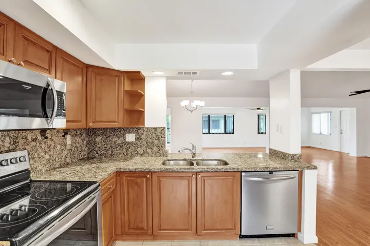 Kitchen featuring wood cabinetry, stainless steel appliances, a double basin sink, and ample countertop space