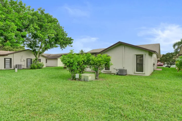 Expansive green lawn with mature trees and established perimeter shrubbery