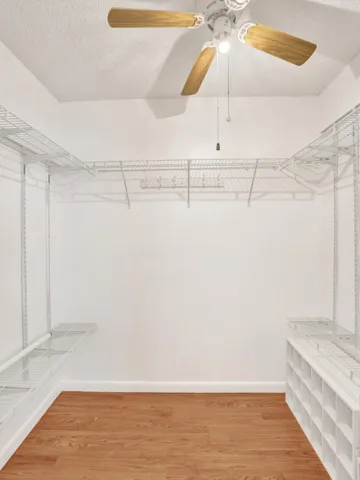 Walk-in closet featuring wood-finish flooring, a ceiling fan, and extensive wire shelving