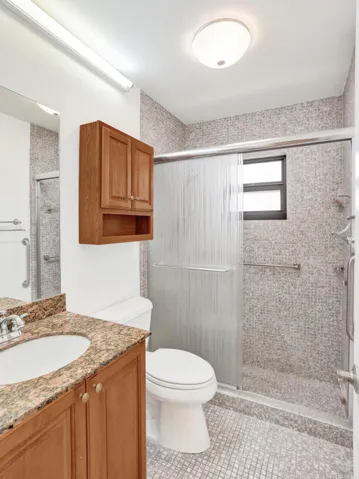 Full bathroom featuring a walk-in shower with sliding glass doors, mosaic tile walls, and a window for natural light