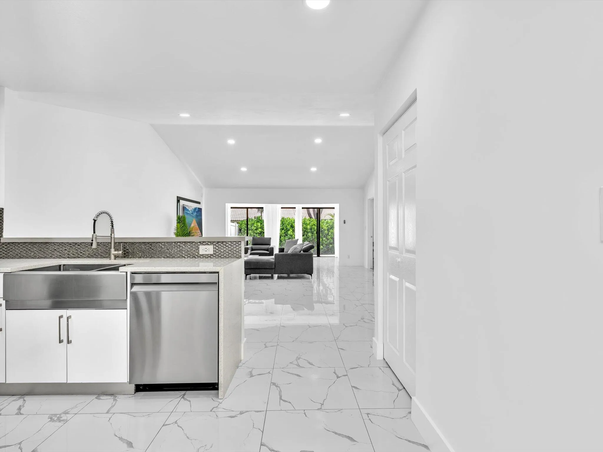 White cabinetry with stainless steel sink and dishwasher, mosaic tile backsplash, recessed lighting, and large format floor tiling
