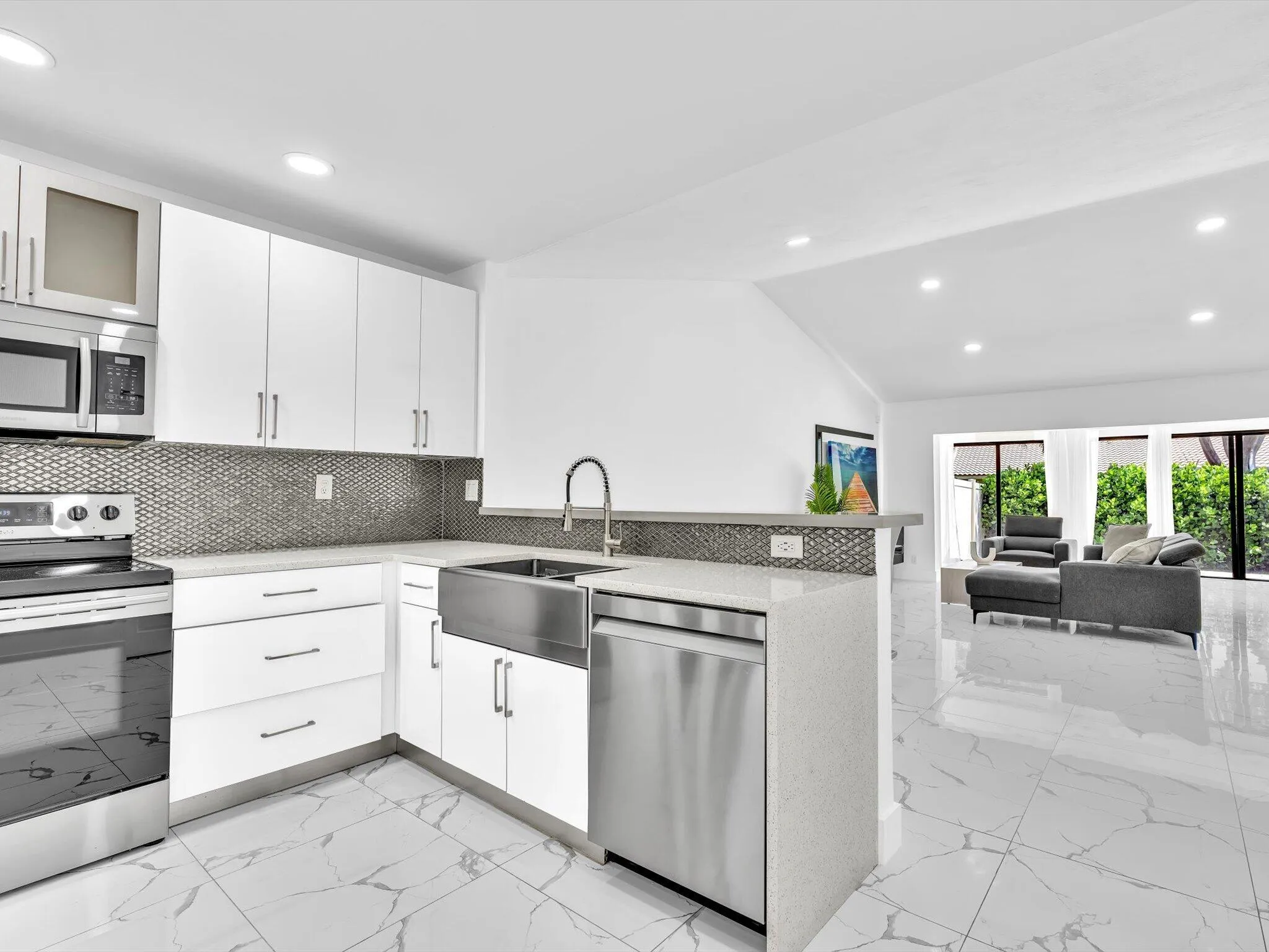 Modern kitchen featuring white cabinetry, stainless steel appliances, a farmhouse sink, and light-toned countertops
